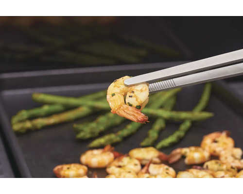 Gegrilde garnalen met asperges, geserveerd met een grilltang.