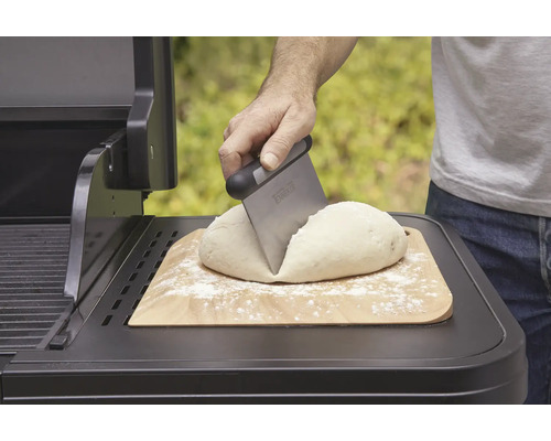 Deeg op houten plank wordt met deegschraper op grill verdeeld