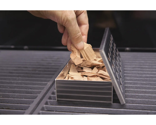 Het vullen van een rookbox met rooksnippers op een barbecue