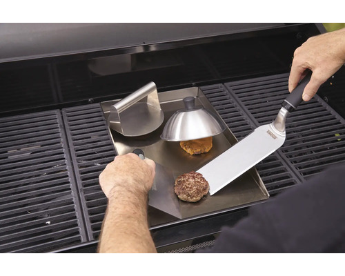 Hamburgers bereiden op een grillplaat met burgerpers en spatel