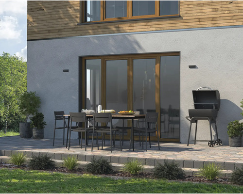 Buitenscène met barbecue, tuintafel en stoelen op een terras voor een woonhuis