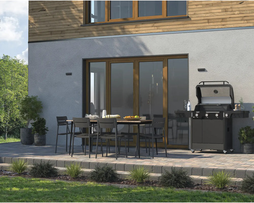 Terras met eettafel, stoelen en gasbarbecue voor een huis.