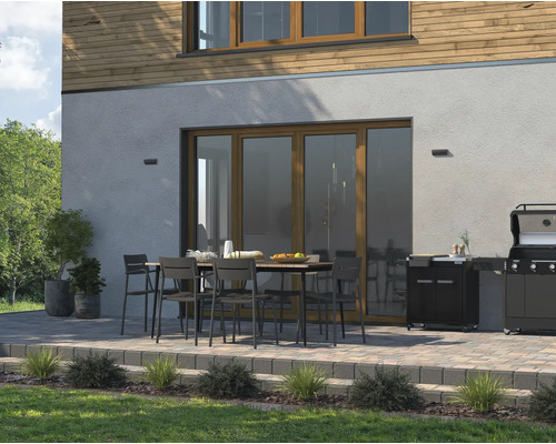 Buitenruimte met tuintafel, stoelen en barbecue op een terras naast een huis.