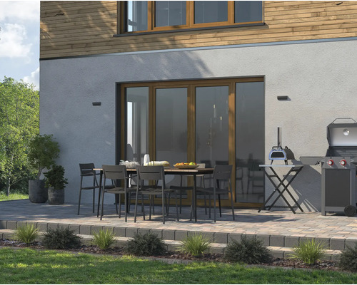 Terras met eettafel, stoelen, barbecue en pizzaoven voor een huis