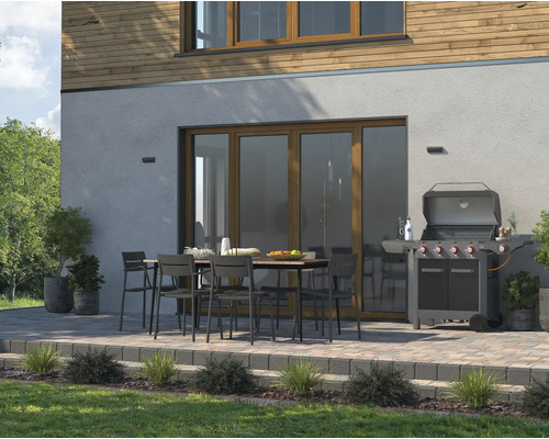 Terras met tuingrill, tafel en stoelen voor een huismuur