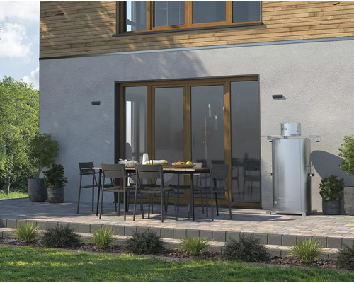 Terras met tuintafel, stoelen en terrasverwarmer voor een huis.