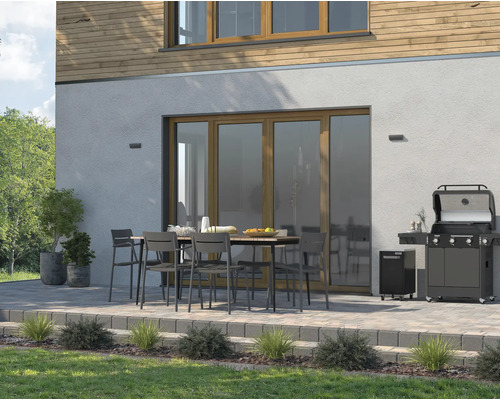 Terras met gasbarbecue, tuintafel en stoelen voor een huis