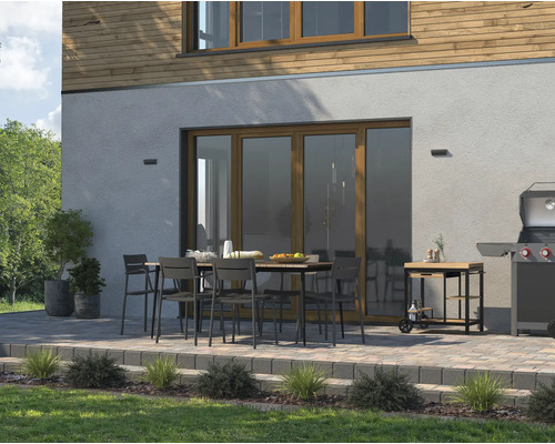 Terras met eettafel, stoelen, barbecue en barbecuekar voor een huis