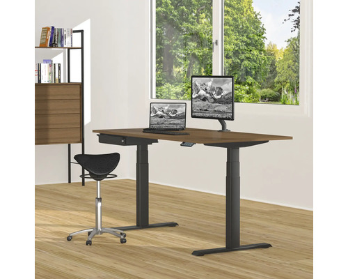 In hoogte verstelbaar bureau met computers, monitor en zadelkruk in een lichte kamer.