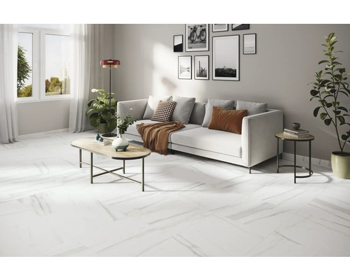 Lichte woonkamer met witte bank, salontafel en witte vloer met marmerlook.