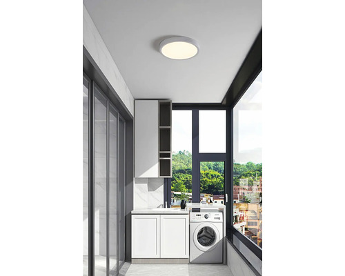 Lichte wasruimte met wasmachine, wastafel, kast en ronde plafondlamp