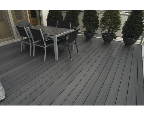 Terras met terrasplanken, eettafel en stoelen buitenshuis.