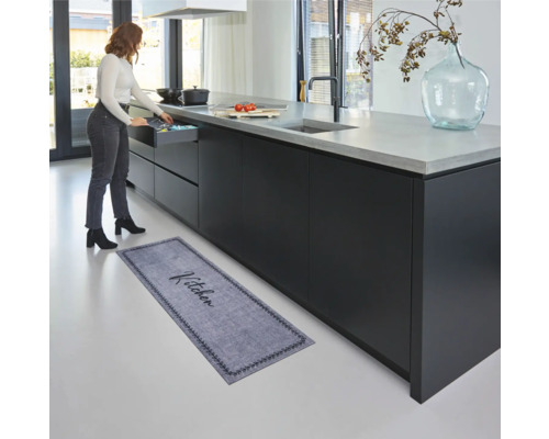 Keukenscène met keukentapijt voor kookeiland en vrouw die een lade opent