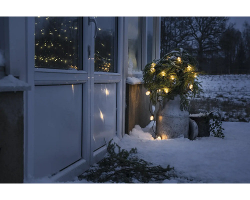 Winterse buitenscène met verlichte sparren voor een voordeur in de sneeuw