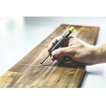 Een hand trekt een lijn op een houten plank met een Pica Longlife Automatic Pencil.