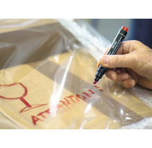 Een man beschrijft een verpakking met een rode stift met het opschrift Voorzichtig glas