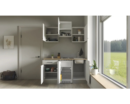 Compacte kitchenette met spoelbak, kookplaat en koelkast in een lichte ruimte