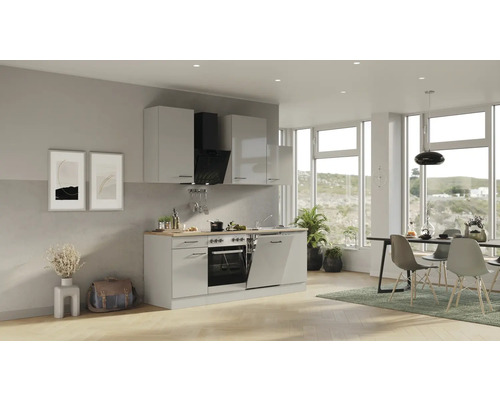 Lichte woonkamer met kitchenette, eettafel en stoelen.