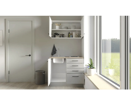 Compacte kitchenette met spoelbak, lades en bovenkast in een lichte ruimte.