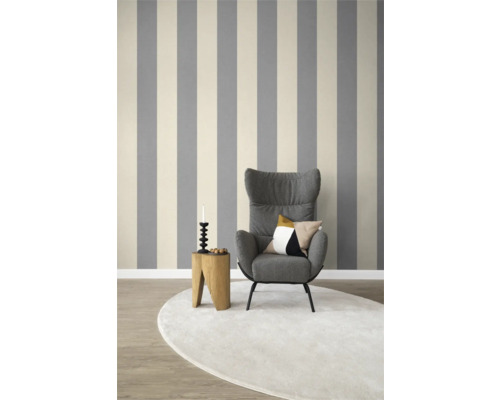 Woonkamer met gestreept behang, fauteuil, vloerkleed en bijzettafel