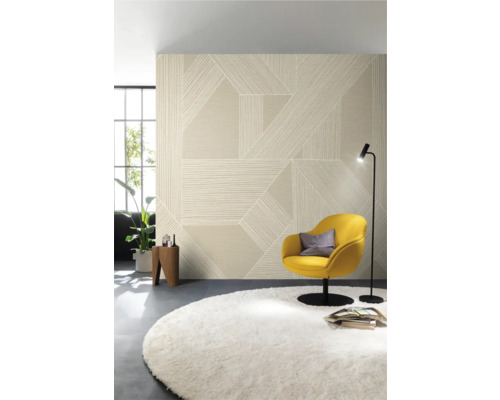 Woonkamer met patroonbehang, fauteuil, vloerkleed en staande lamp.