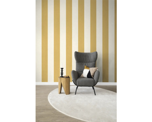 Woonkamer met fauteuil, bijzettafel, decoraties en gestreept behang