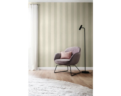 Gestreept behang met fauteuil, kussen, lamp en vloerkleed in een lichte kamer.