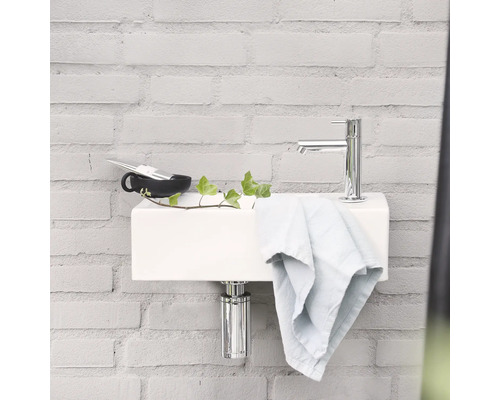 Moderne badkamer met witte wastafel, chromen kraan en handdoek tegen een bakstenen muur