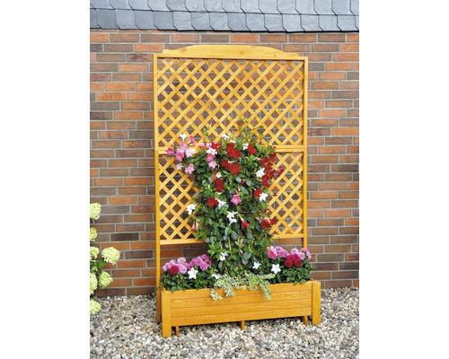 Houten plantenbak met klimrek en bloeiende planten voor een bakstenen muur