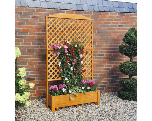 Houten trellis met plantenbak en bloemen voor een bakstenen muur