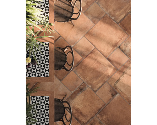 Vloer met terracotta tegels, tafels en stoelen.