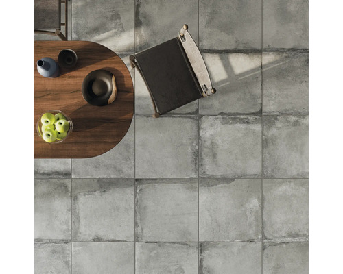 Bovenaanzicht van een vloeroppervlak met vierkante tegels, een tafel met decoratie en een stoel.