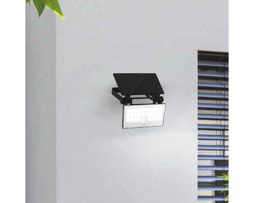 Zwarte LED-buitenstraler met bewegingssensor aan een muur gemonteerd.