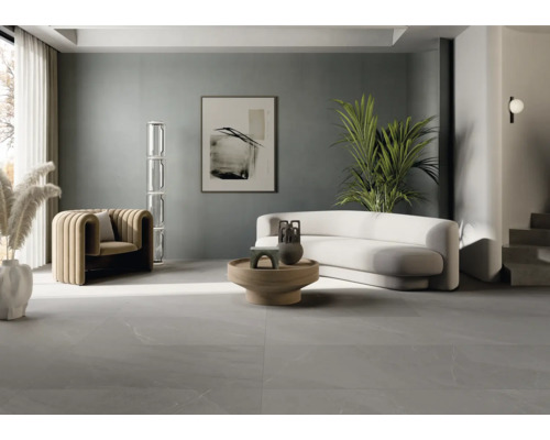 Lichte woonkamer met bank, fauteuil, tafel en grijze vloertegels