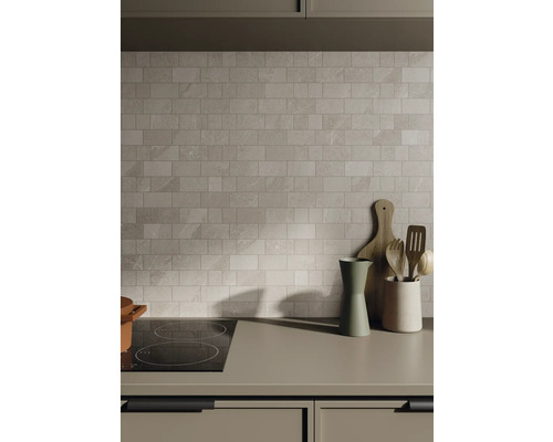 Keukenscène met tegelwand, kookplaat en keukengerei op het aanrecht.