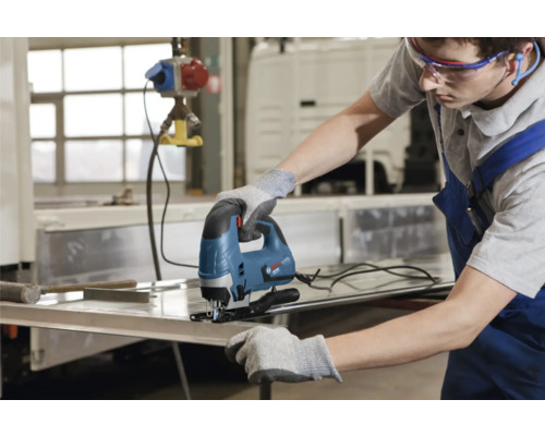 Een man gebruikt een decoupeerzaag om metaal te snijden.