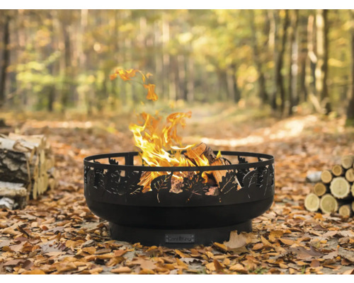 Vuurschaal met bladmotief en brandend hout in de tuin