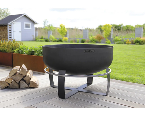 Stalen vuurschaal op een houten tuinterras met een stapel hout