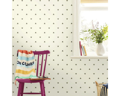 Kamerbeeld met behang met bijenpatroon, stoel, deken en raam.