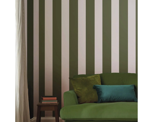 Woonkamer met gestreept behang, groene bank en bijzettafel met boeken.