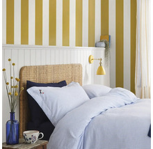 Slaapkamer met bed, blauw gestreept beddengoed en geel gestreept behang