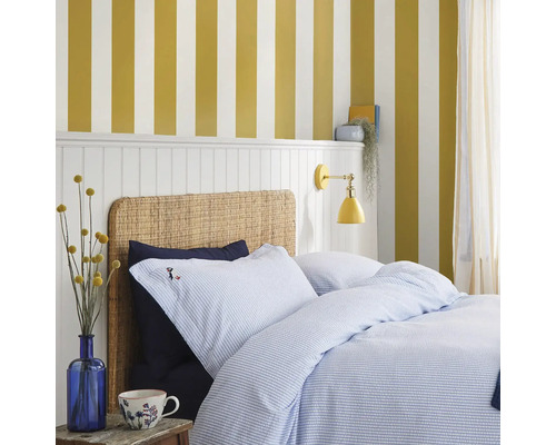 Slaapkamer met bed, blauw gestreept beddengoed en geel gestreept behang