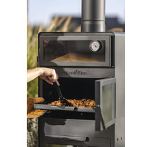 Een man schuift een maaltijd met een spatel in een Cook King buitenoven.