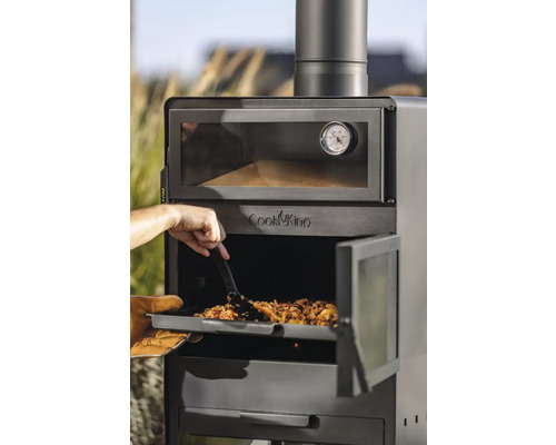 Een man schuift een maaltijd met een spatel in een Cook King buitenoven.