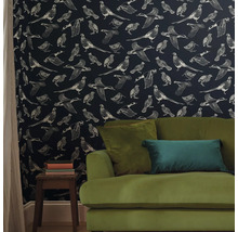 Woonkamer met patroonbehang met vogelmotieven en een groene bank.