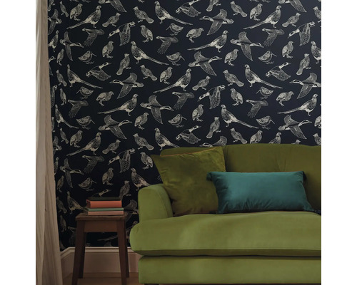 Woonkamer met patroonbehang met vogelmotieven en een groene bank.