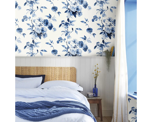 Slaapkamer met bloemenbehang, bed met gestreept beddengoed en gebreide deken