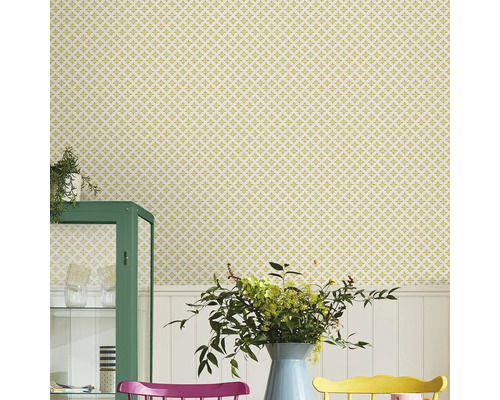 Scene met een bloemetjesbehang, een groene kast en een eettafel met kleurrijke stoelen.