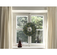 Gedecoreerd raam met kerstkrans, gordijnen en decoratieve boom.