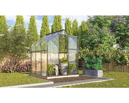 Glazen en metalen serre in de tuin met planten